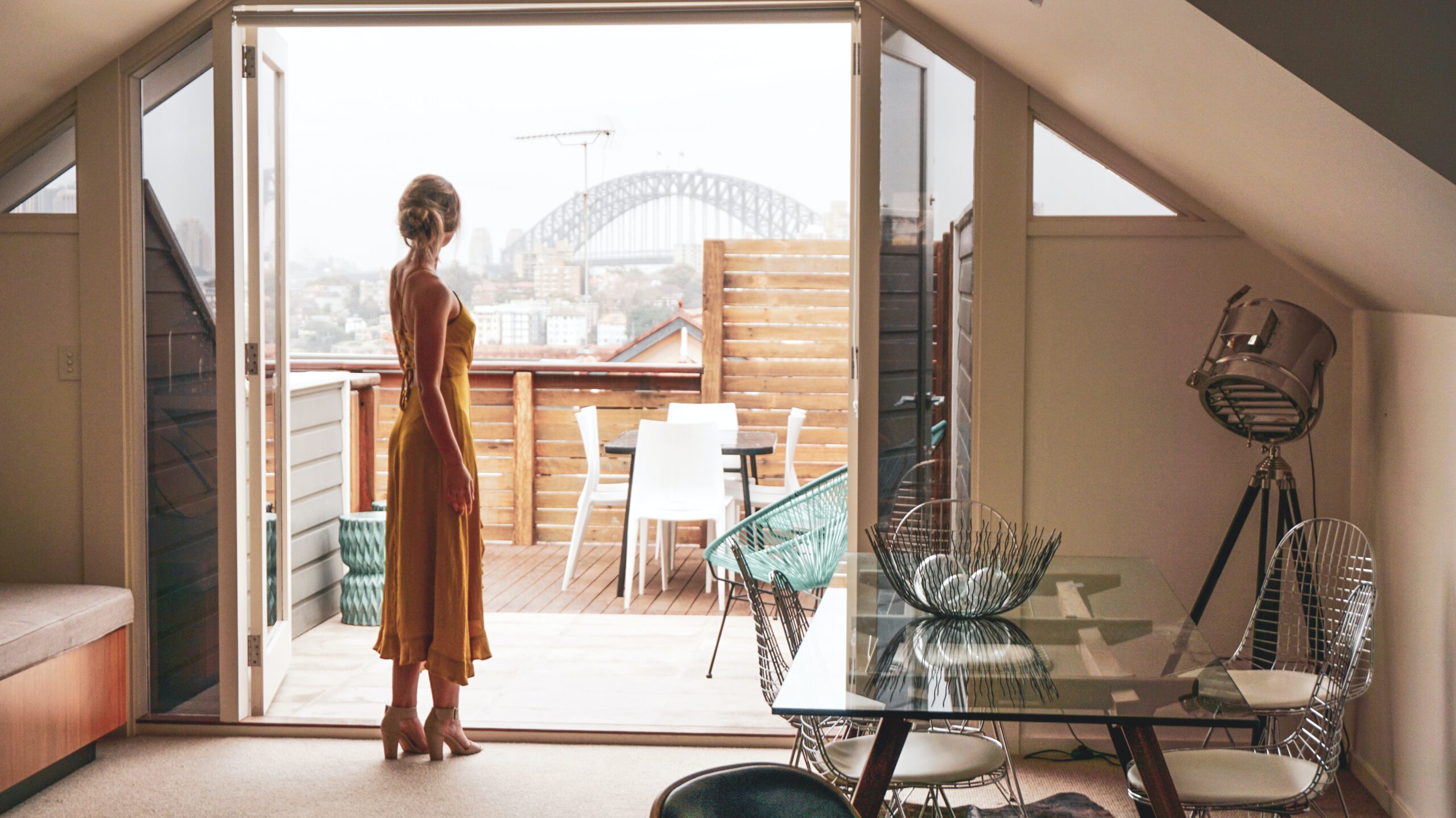 Kobieta w sukience stojąca w salonie w drzwiach balkonowych